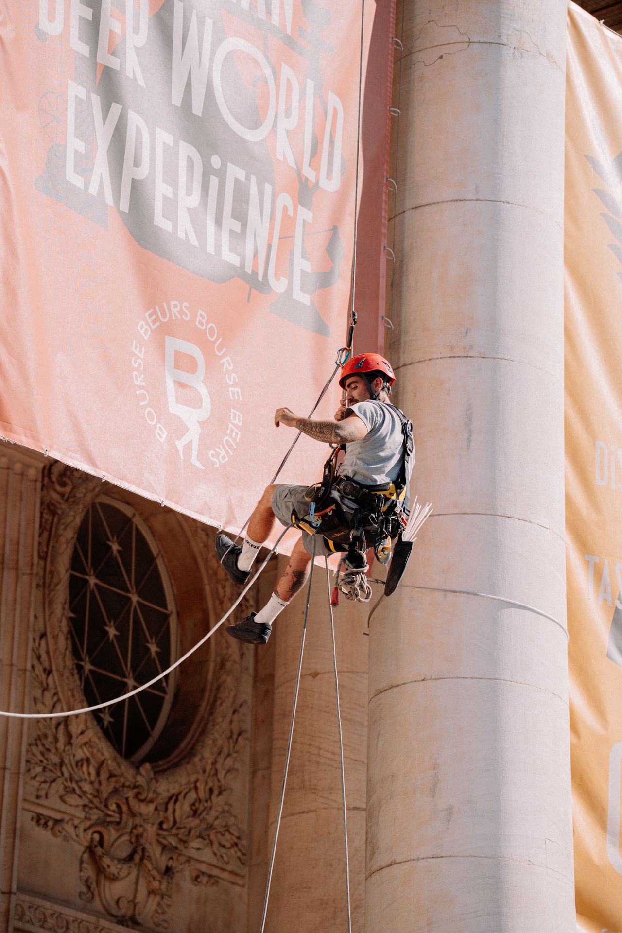 Installation d'une bâche publicitaire grand format sur un bâtiment historique à Bruxelles par un cordiste spécialisé en événementiel.