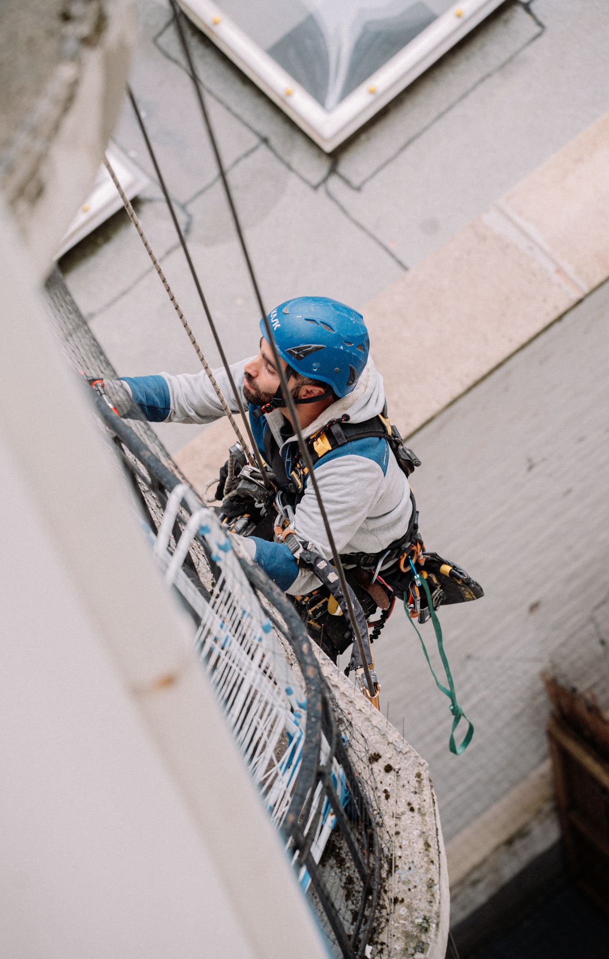 technicien cordiste des Suspendus, équipé de son harnais et de son matériel de sécurité, en intervention sur une façade
